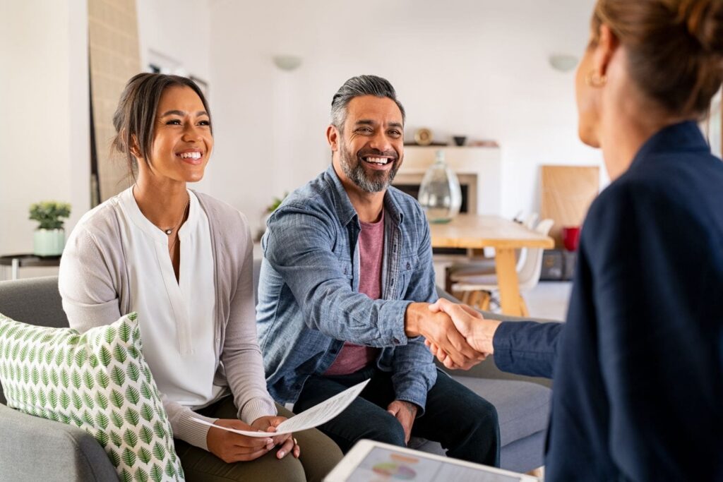 A happy couple of new clients shaking hands with their attorney or consultant after a successful meeting. Their smiles signify the trust and satisfaction that results from the seamless and professional client acquisition process created by the Firm Heartbeat experience.