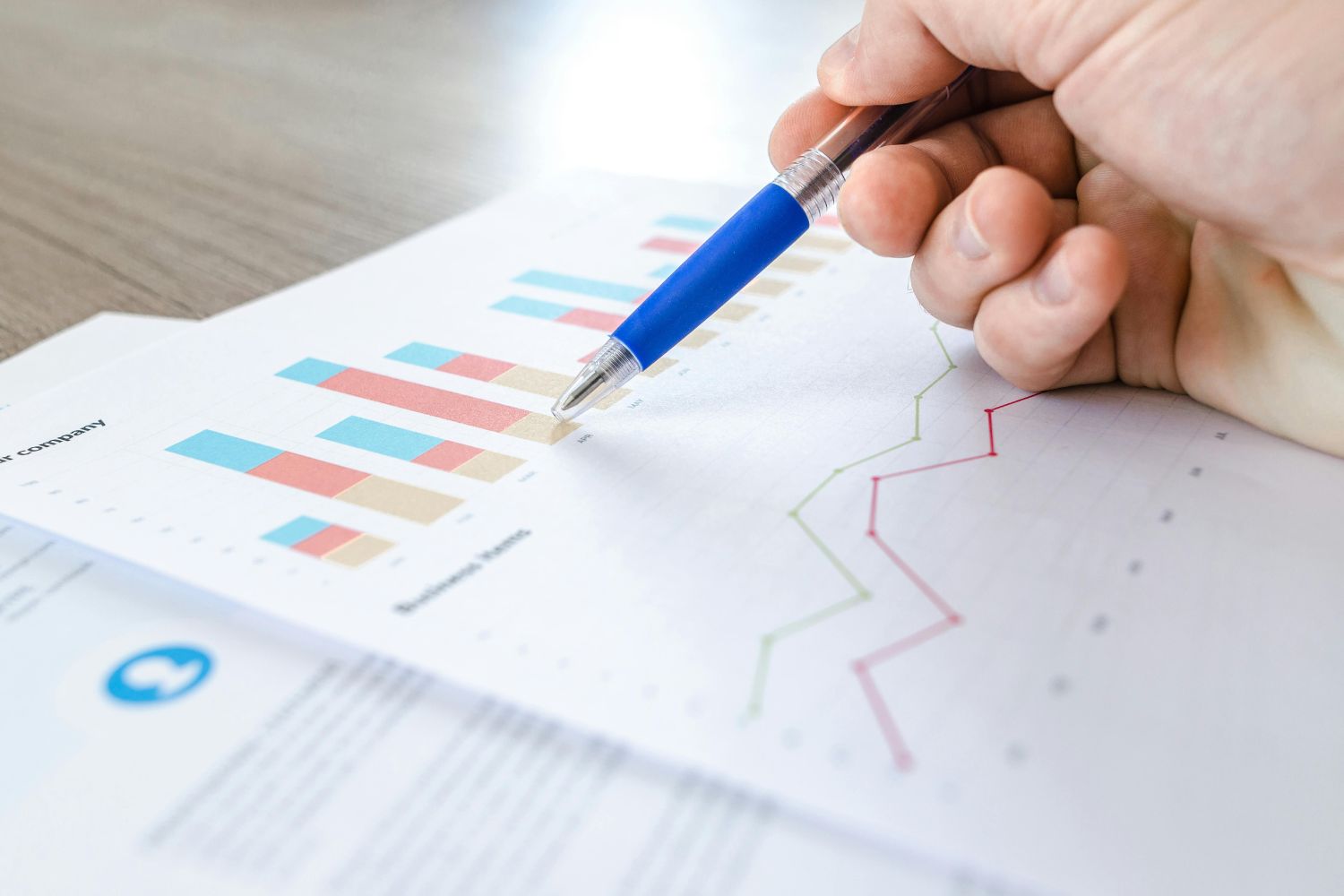 A business professional's hand holding a blue pen and pointing to a colorful bar chart on a conversion analysis report. This image represents the data-driven insights and measurable results that the Firm Heartbeat experience provides to law firms to track intake performance and guide strategic growth.