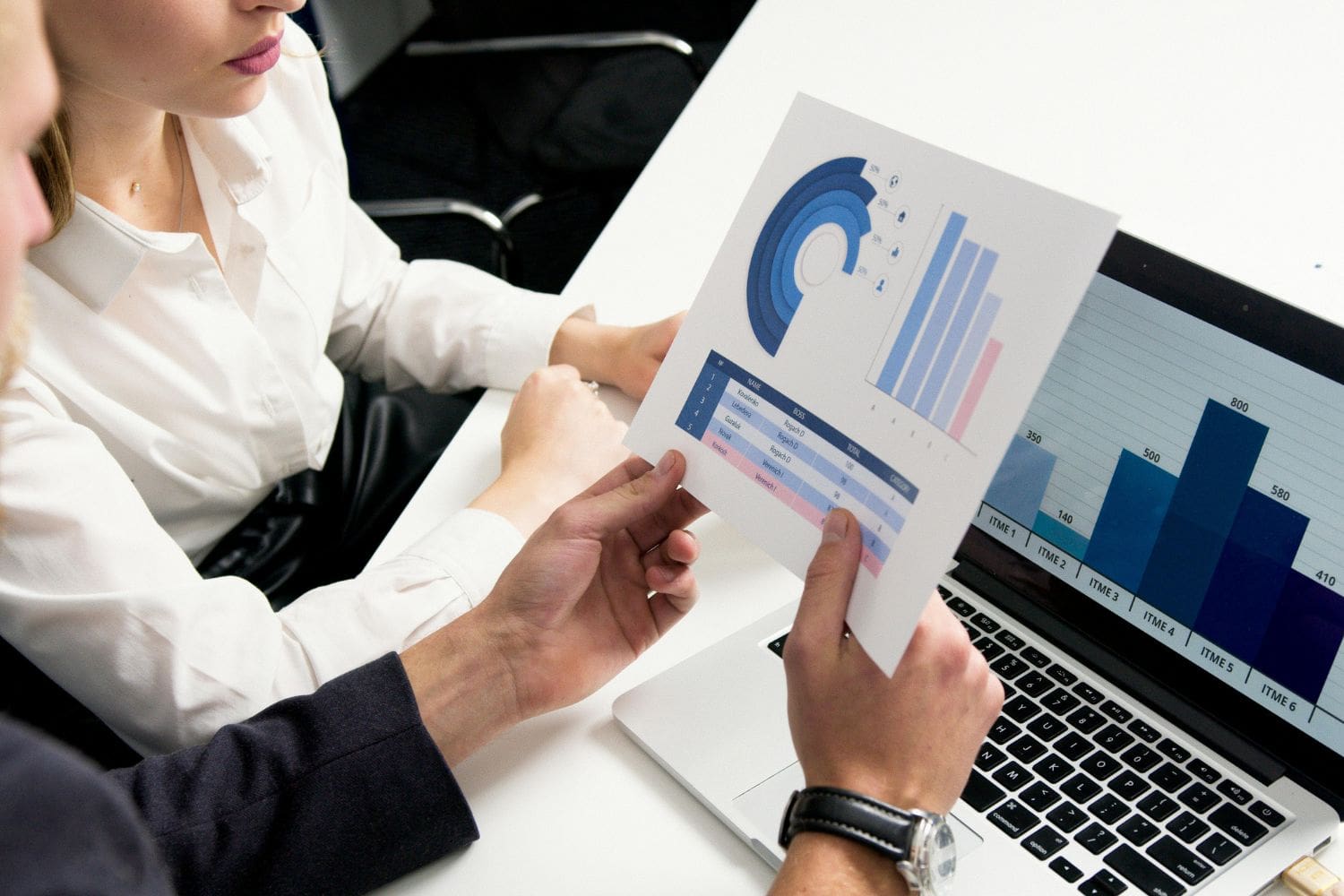 A Firm Heartbeat consultant and a law firm partner collaboratively reviewing a data report with charts and graphs. The report, showing key performance indicators for the firm's intake, represents our commitment to data analysis, measurable results, and continuous strategic improvement.
