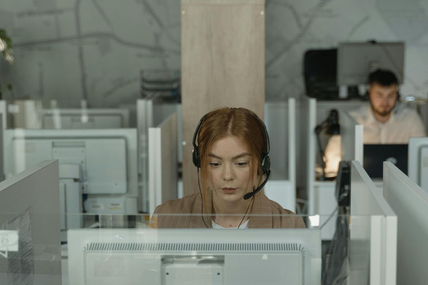 A focused female intake specialist for a law firm, wearing a headset and concentrating on her computer screen in a modern, structured office environment. Her diligent focus represents the disciplined, process-driven intake and sales system installed by the Firm Heartbeat experience to ensure consistent results.