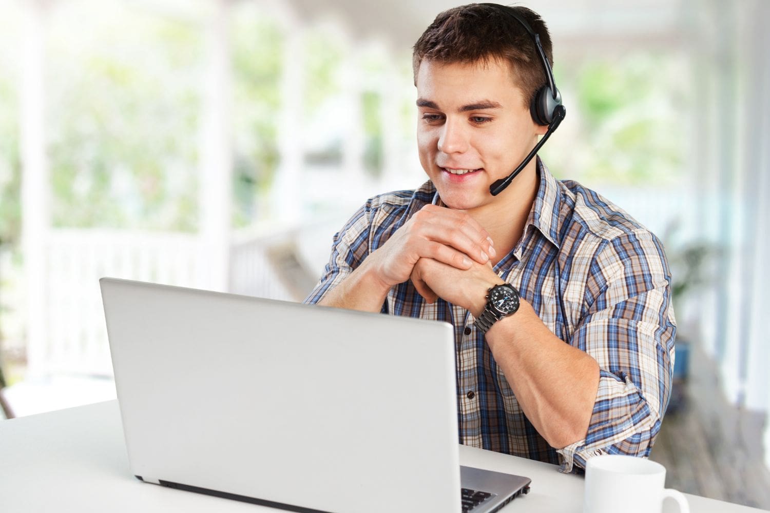A professional male intake specialist wearing a headset sits at his desk, attentively engaging with a potential client on his laptop. He has a positive, focused expression, representing an efficient and successful law firm client intake process implemented by Firm Heartbeat.