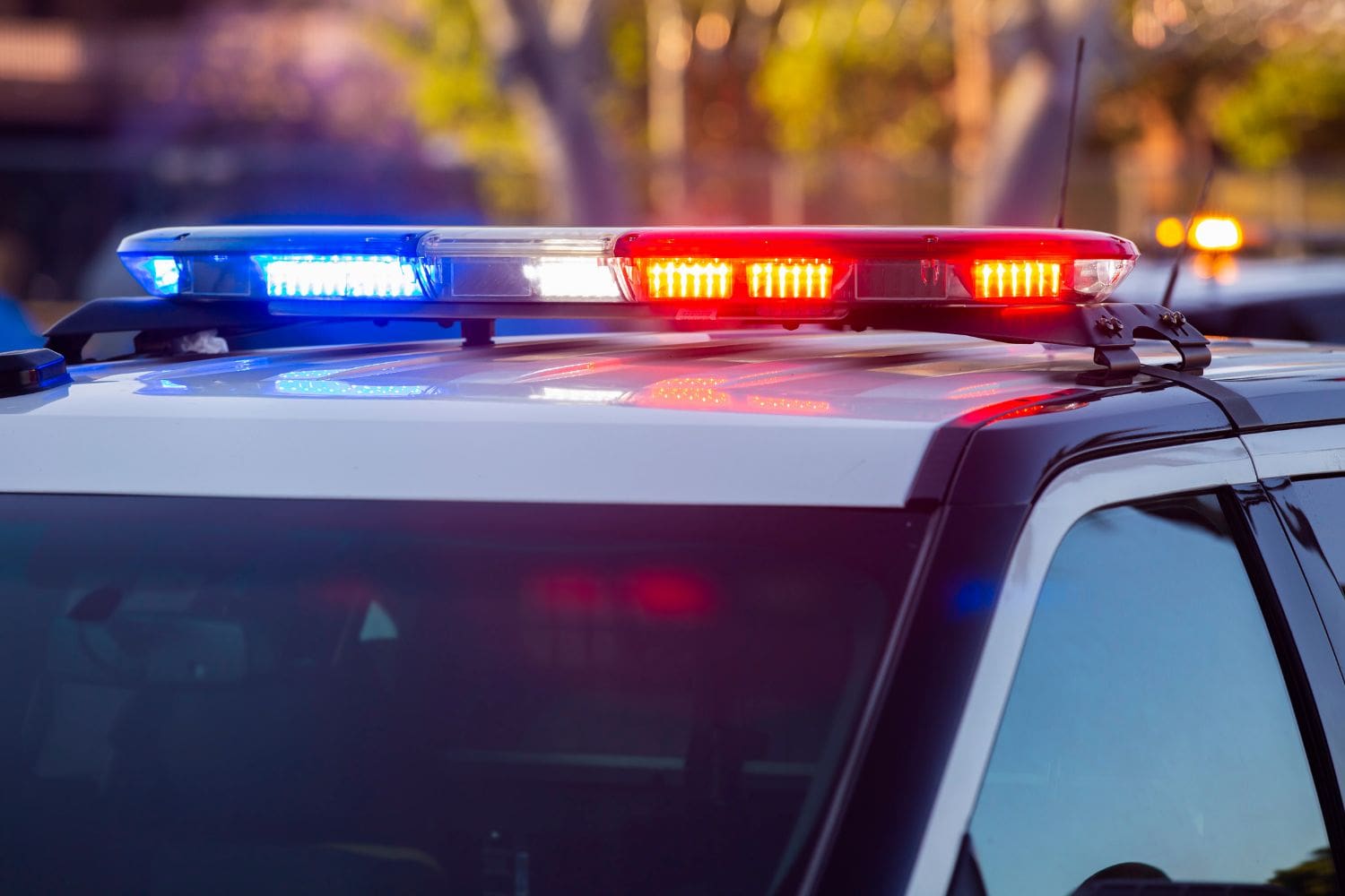 The flashing red and blue lights on a police car's roof, symbolizing a client's legal crisis. This urgent moment represents the critical, time-sensitive opportunity that a law firm's intake process, repaired by the Firm Heartbeat experience, must be ready to capture 24/7.