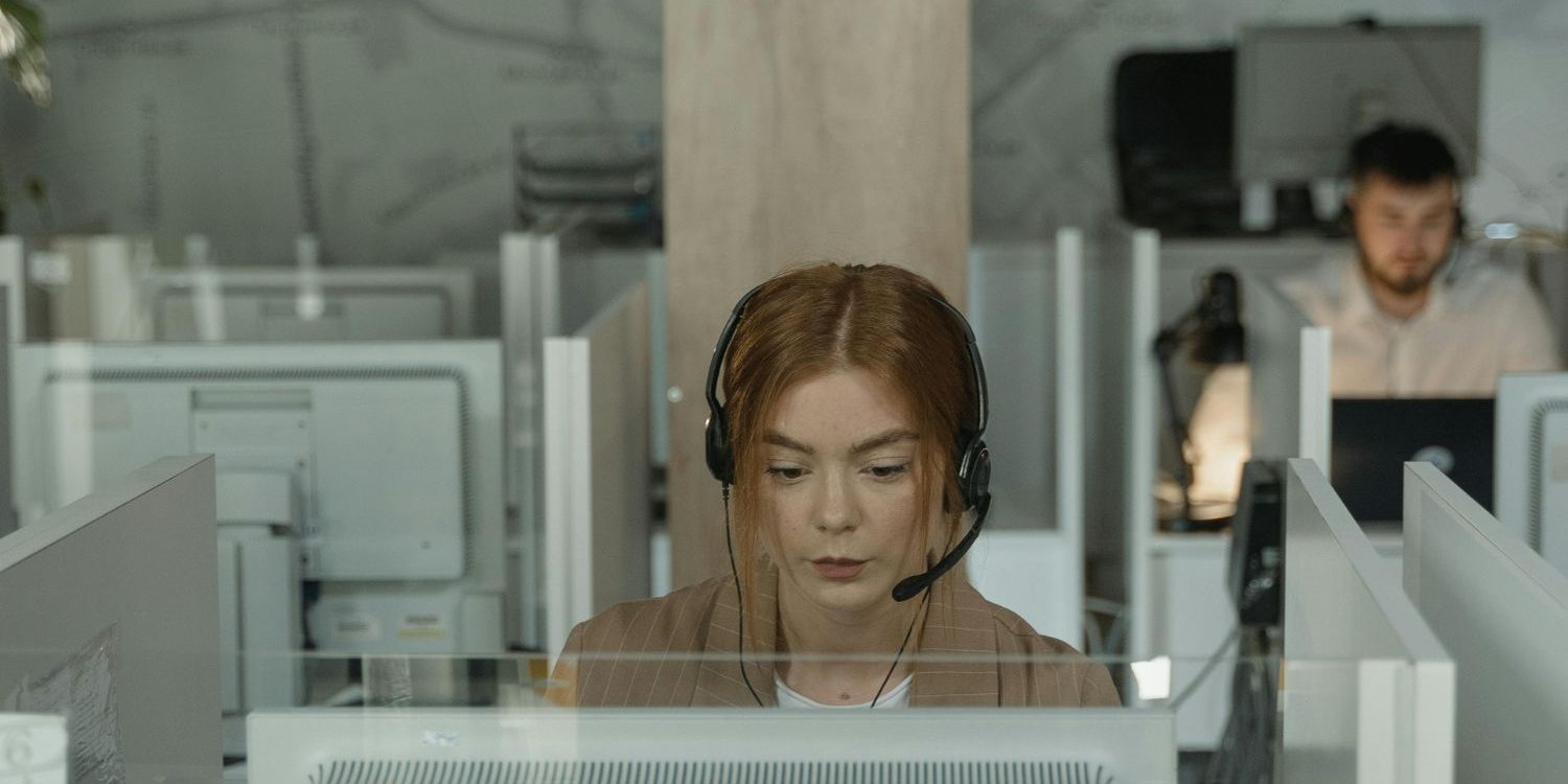 A focused female intake specialist for a law firm, wearing a headset and concentrating on her computer screen in a modern, structured office environment. Her diligent focus represents the disciplined, process-driven intake and sales system installed by the Firm Heartbeat experience to ensure consistent results.